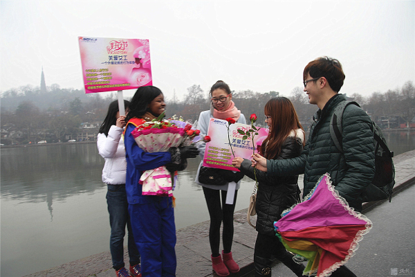 外籍女工西湖邊“關愛女工”行為體驗 游人的熱情擁抱累得她胳膊抬不起來